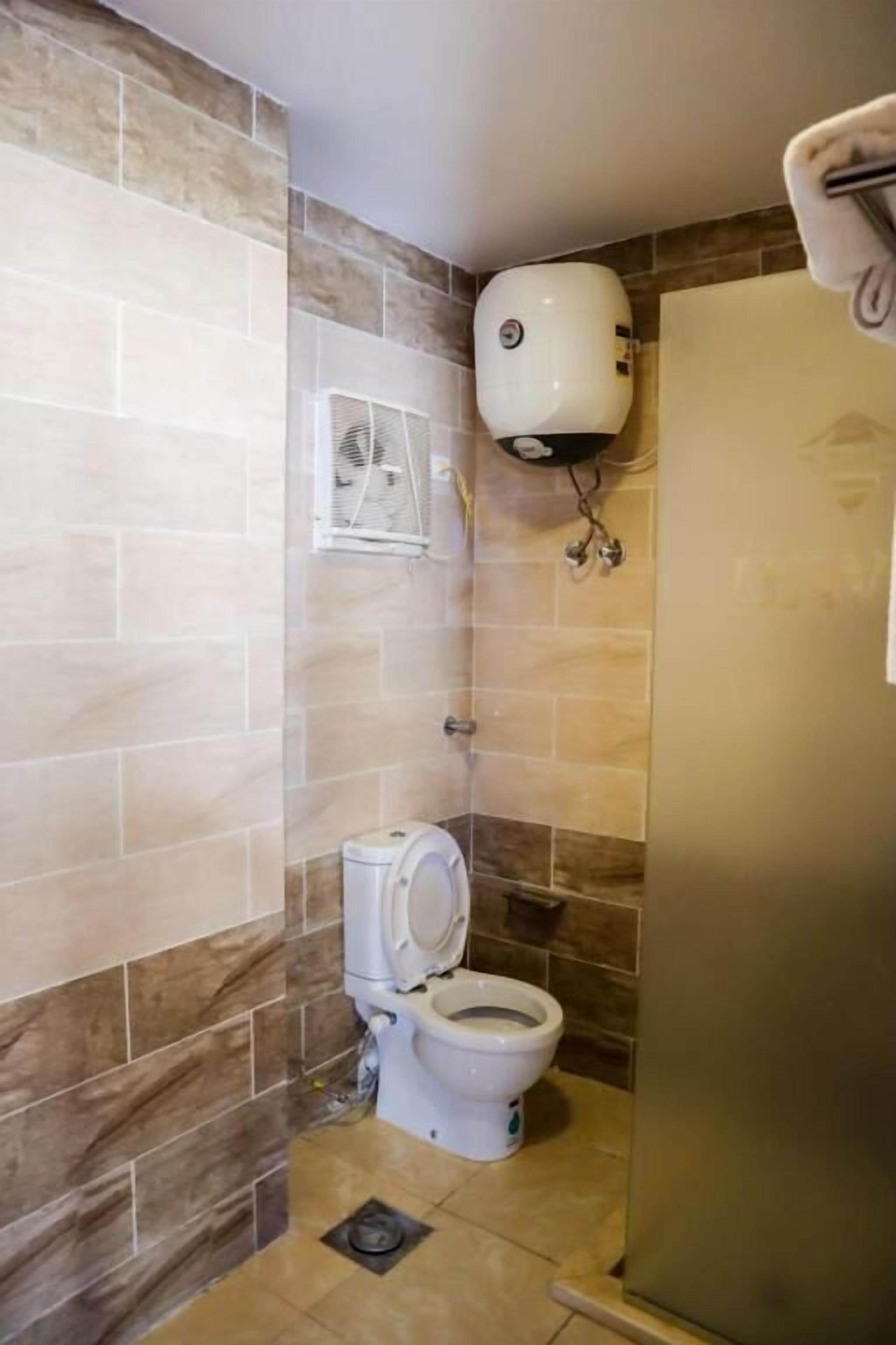 A bathroom with a toilet, a wall-mounted air freshener, and a shower area.