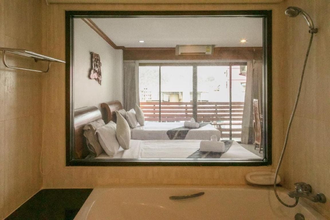 A hotel room with a large bed, a bathtub, and a view of a balcony.