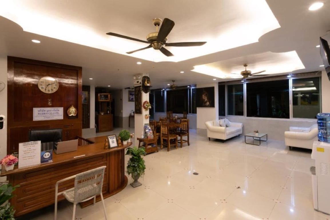A hotel reception area with a reception desk, seating area, and a large window.