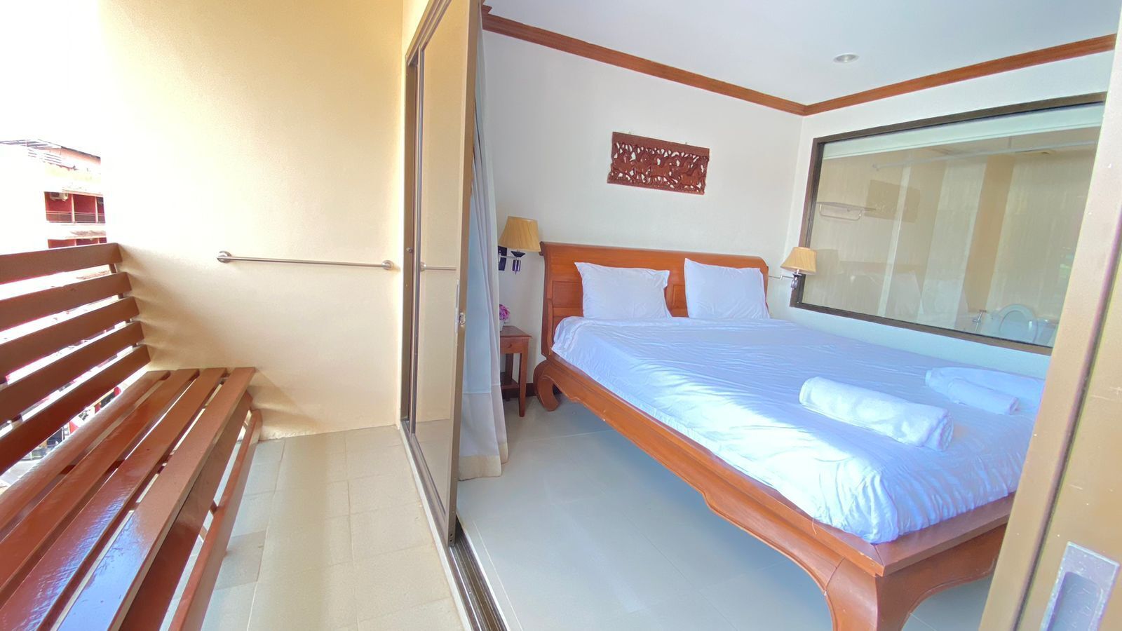 A bedroom with a wooden bed, a nightstand, a lamp, and a window.