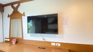 A wall-mounted TV with a remote control on a wooden counter. - Best Venue Hotel (Patong)