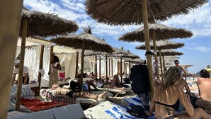 Une plage avec des parasols en chaume et des chaises longues.