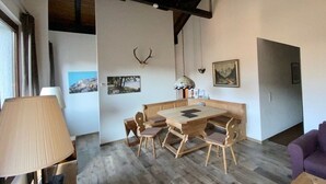 Un coin repas avec une table et des bancs en bois, une lampe et des décorations murales, notamment une tête de cerf et des tableaux encadrés.