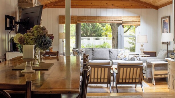 A spacious dining area with a wooden table, chairs, and a ceiling fan. - 1000 FT to Assn Beach, Cute Cottage, Outdoor Dining (Lakeside)