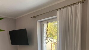 A room with a wooden cabinet, a flat-screen TV, a sliding glass door, and a potted plant. - Ferienhaus Albertus (Cottbus)