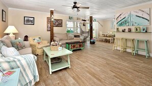 A cozy living room with a sofa, a coffee table, a hammock, and a dining area with a table and chairs. - Three Bedroom Waterfront Home with a Rooftop Deck (Ocean City)