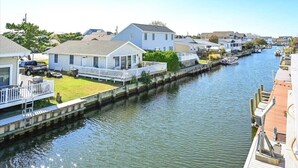 A canal with houses on either side, a dock, and a clear sky. - Three Bedroom Waterfront Home with a Rooftop Deck (Ocean City)
