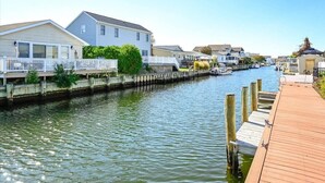 A waterfront property with a dock, houses along the water, and a clear sky. - Three Bedroom Waterfront Home with a Rooftop Deck (Ocean City)