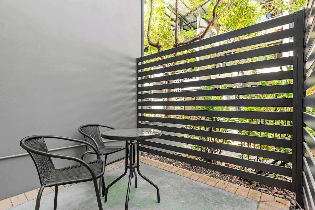 Un balcon avec une balustrade en métal, deux chaises et une petite table ronde.