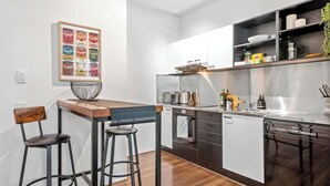 Una cocina moderna con una isla central, taburetes de bar, una cafetera y un cartel de comida en un marco.