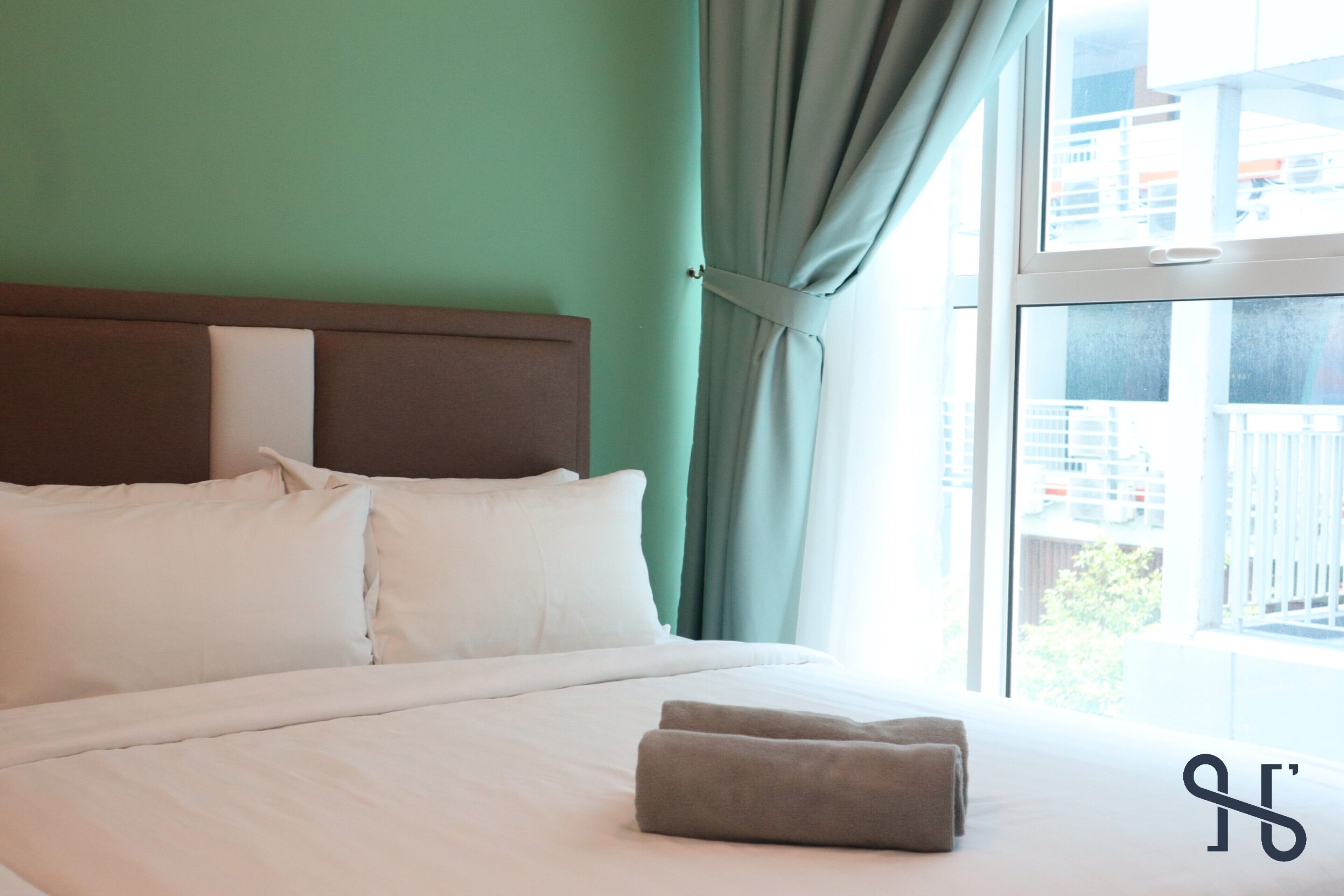 A hotel room with a bed, white bedding, a headboard, and a view of buildings through a window.