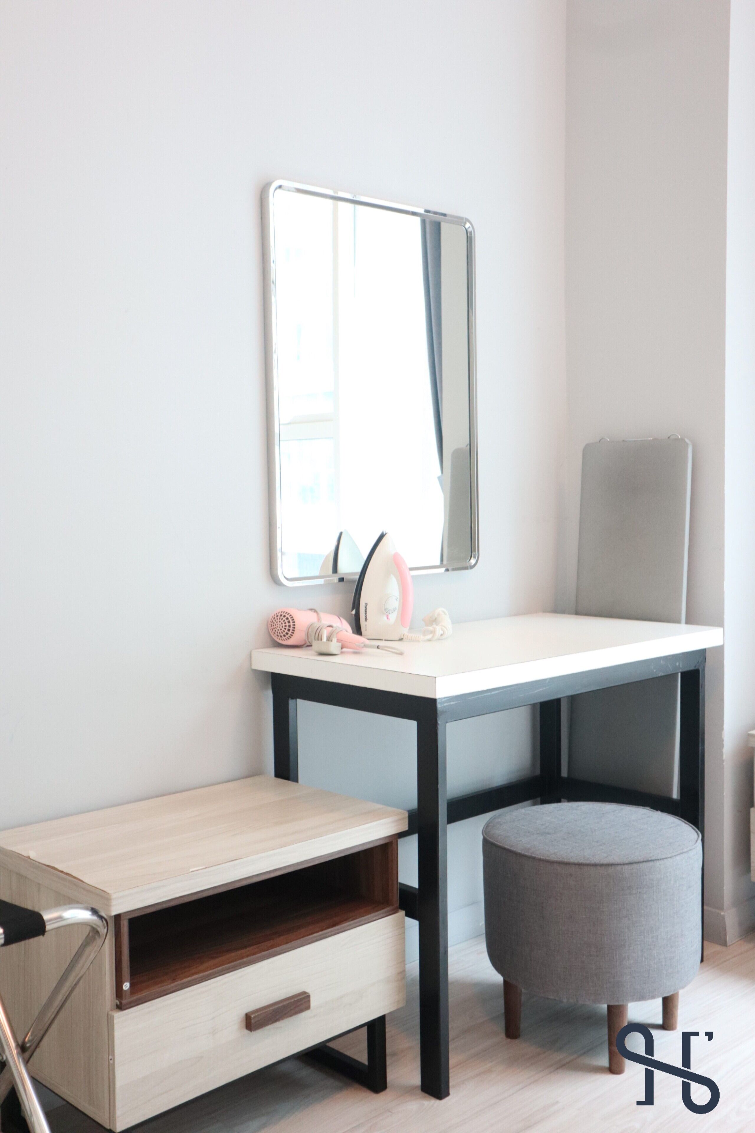 A modern bathroom with a wooden vanity, a mirror, and a grey ottoman.