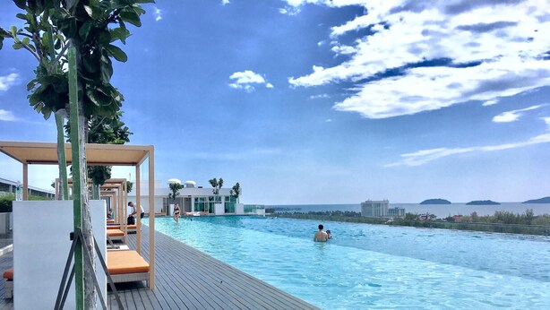 A poolside area with lounge chairs and a wooden deck. - Homesuite' Home at Sutera Avenue (Kota Kinabalu)