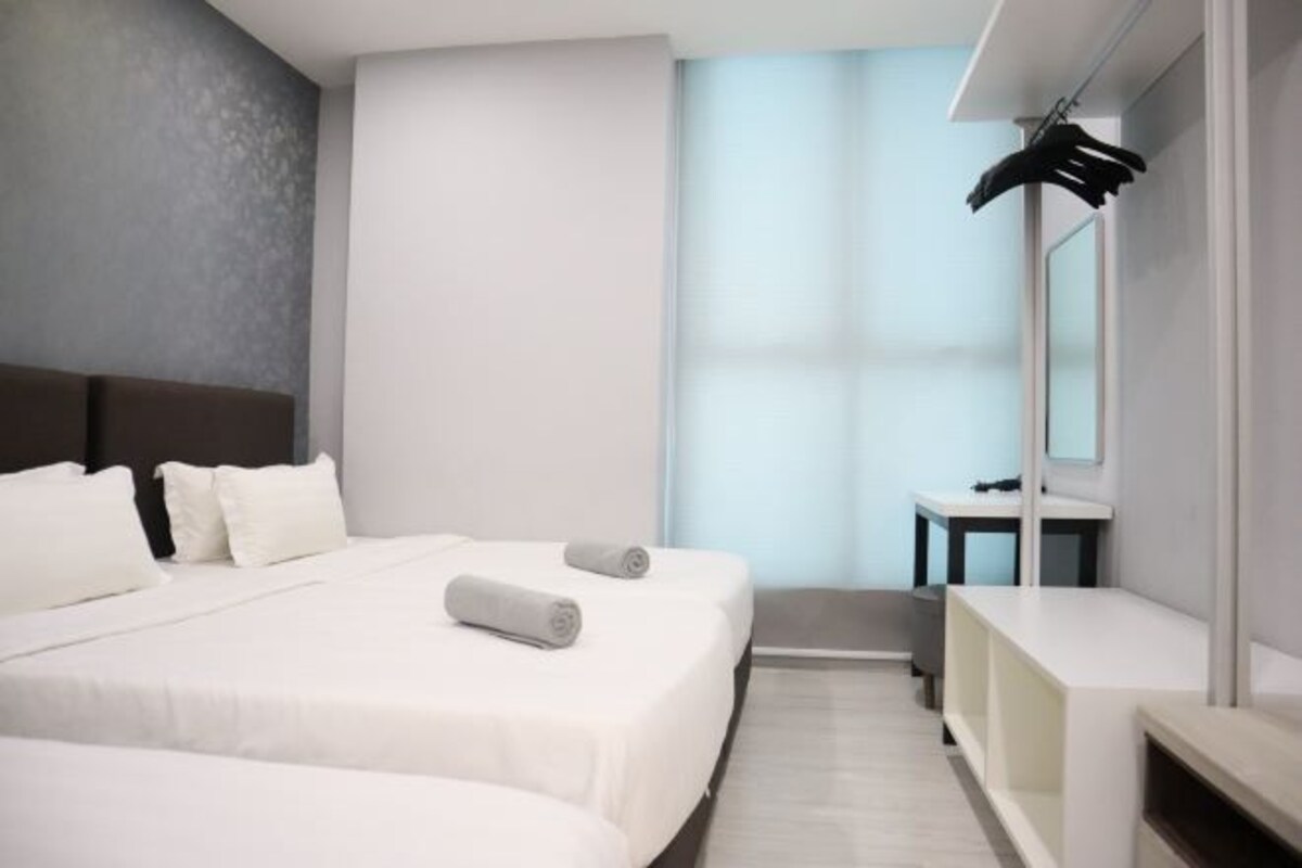 Une chambre d’hôtel moderne avec deux lits, un petit bureau et un miroir.