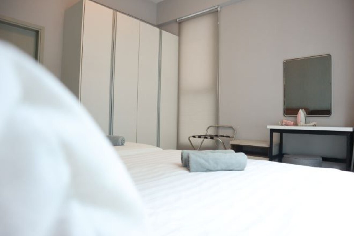 Een moderne hotelkamer met een bed, een bureau, een stoel en een kledingkast.
