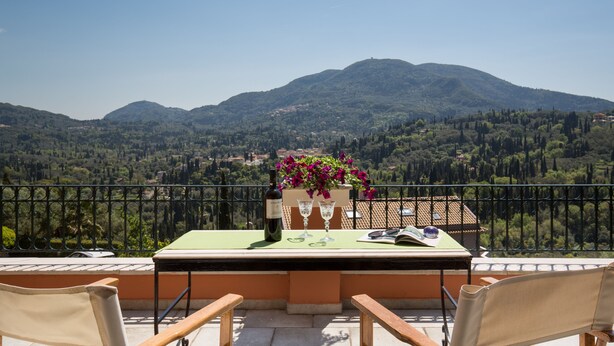 Eine Terrasse mit Tisch für Zwei, mit Blick auf eine gebirgige Landschaft.