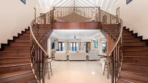 Un vaste espace de vie agrémenté d’un escalier en bois menant à un balcon.