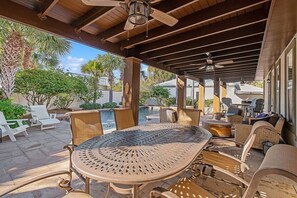 An outdoor patio with a round table, chairs, and a ceiling fan.