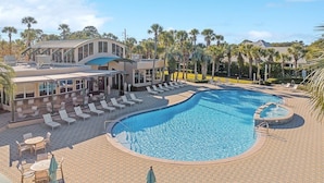 A resort with a large swimming pool, sun loungers, and a covered seating area.