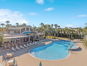 Un resort con una amplia piscina, tumbonas y una zona de estar cubierta.