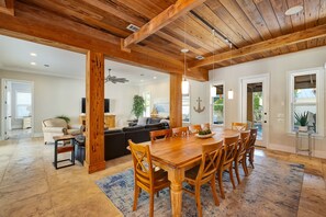 A spacious living area with a wooden dining table, comfortable seating, and a ceiling fan. - Seas The Day | Destiny East Neighborhood | Private Pool | Golf Cart! (Destin)