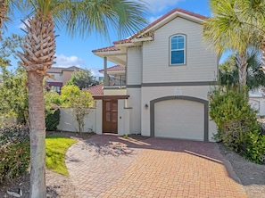 A two-story house with a garage, a balcony, and a well-maintained garden. - Seas The Day | Destiny East Neighborhood | Private Pool | Golf Cart! (Destin)