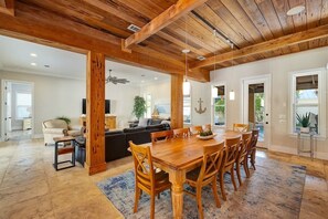 A spacious living area with a wooden dining table, sofas, and a large window.