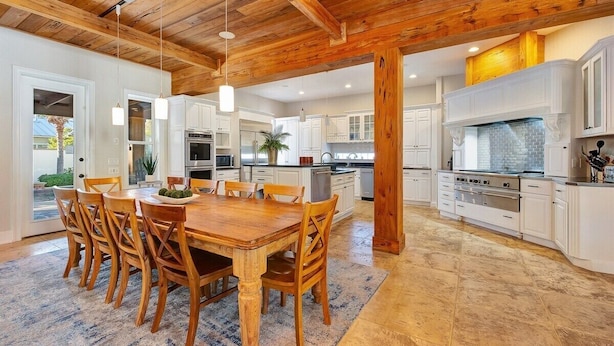 A spacious kitchen with white cabinetry, a wooden dining table, and a large island with a built-in oven.