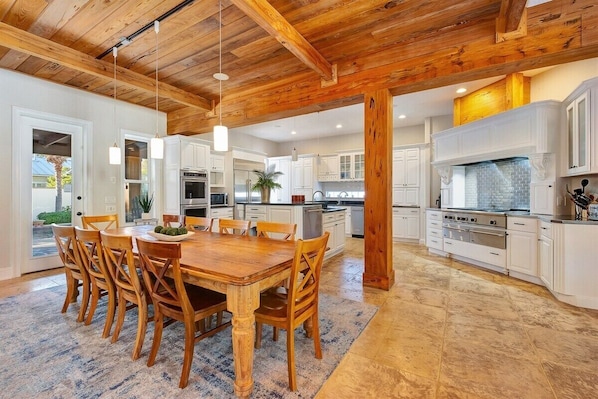 Una cocina amplia con armarios blancos, una mesa de comedor de madera y una isla grande con horno integrado.