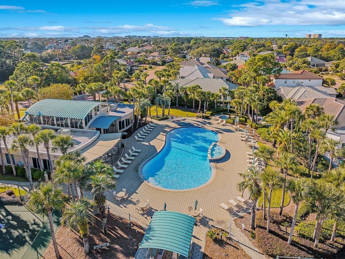 A resort with a large swimming pool surrounded by palm trees and lounge chairs.