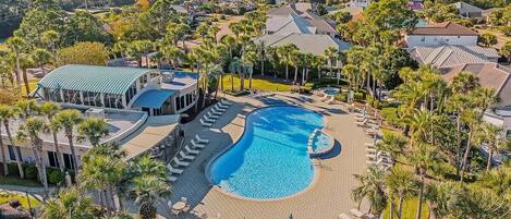 A resort with a large swimming pool surrounded by palm trees and lounge chairs.