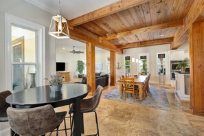 A spacious kitchen with a dining area, wooden ceiling beams, and a large window.