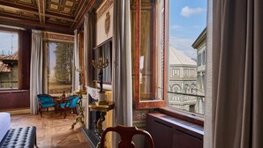 A room with a large window, a fireplace, and a view of a historic building. - Duomo Luxury Florence (Florence)