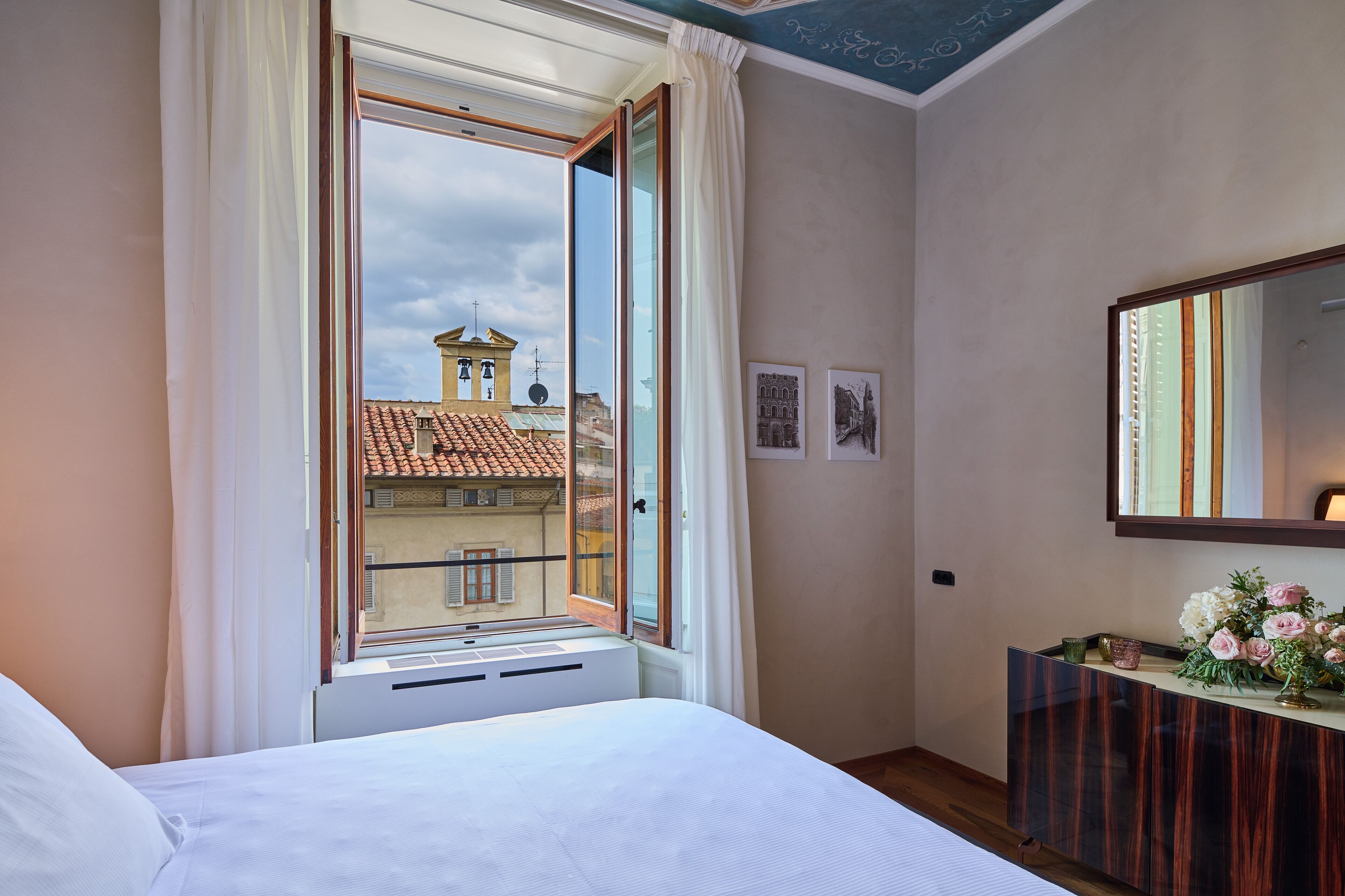 A bedroom with a large window, a bed, a dresser, and a mirror.