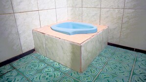 A bathroom with a blue bathtub, green patterned floor tiles, and white walls. - SPOT ON 93210 Griya Kos Kanjeng Mami Syariah (Jogoroto)