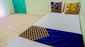 A bed with a blue and yellow patterned bedspread and pillows, a green door, and a tiled floor. - SPOT ON 93210 Griya Kos Kanjeng Mami Syariah (Jogoroto)