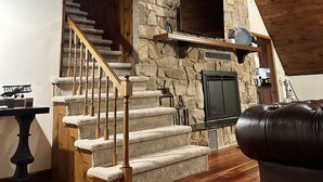A stone fireplace with a wooden staircase leading to a loft.