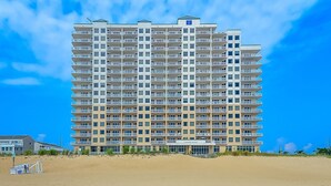 Ein mehrstöckiges Hotel mit Balkonen in der Nähe eines Sandstrandes.