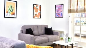 A modern living room with a grey sofa, a yellow throw blanket, and framed artwork on the wall. - Perfect for Family & Corporates - FREE Parking - Contact us for better rates! (Headingley)