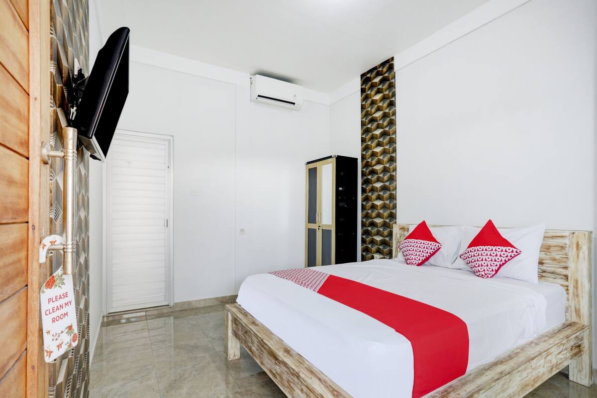 Une chambre à coucher comprenant un lit, une armoire, un téléviseur et un climatiseur fixé au mur.