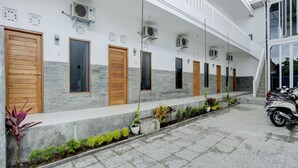 A building with multiple doors, air conditioning units, and a tiled courtyard with potted plants. - OYO Flagship 90756 Melasti Hills Room & Cafe (Ungasan)