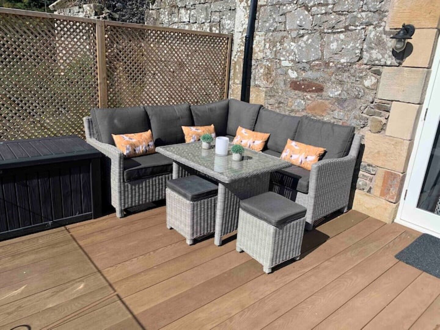 A patio with a wicker sofa set, a table, and a small side table.
