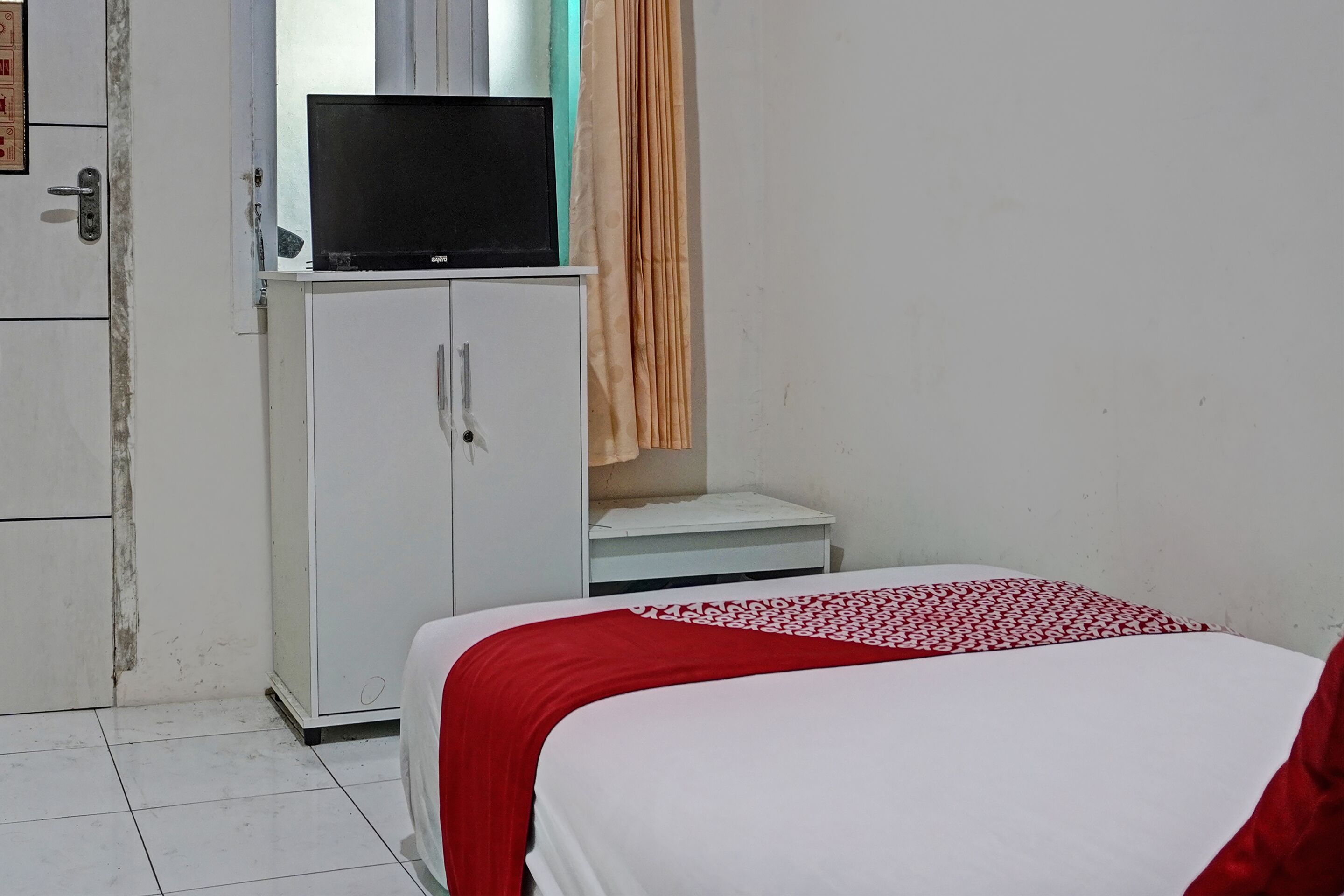 Ein Hotelzimmer mit Bett, Fernseher auf einem Schrank und einem kleinen Tisch.