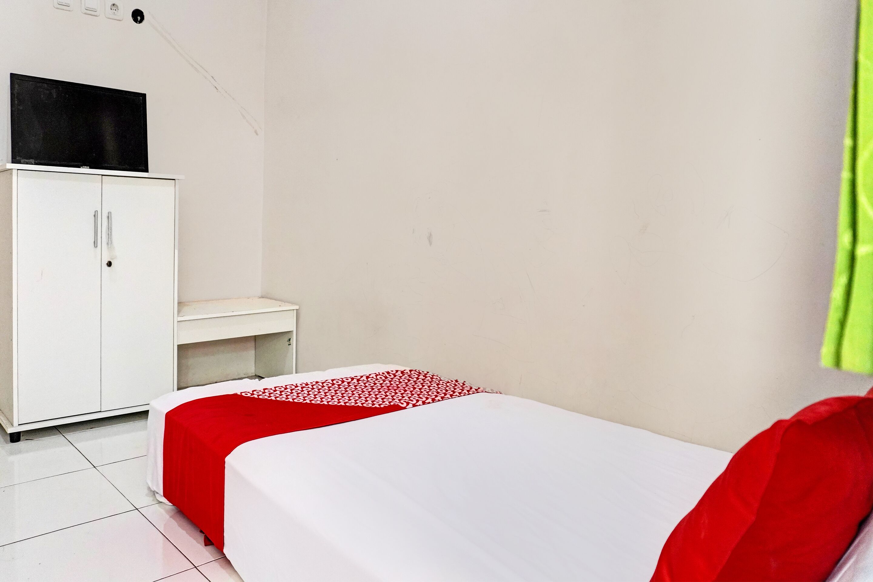A small, clean room with a bed, a white wardrobe, and a desk.