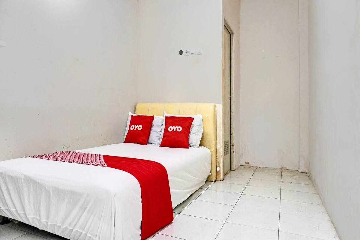 A small, clean room with a bed, white walls, and a tiled floor.