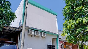 A building with a white facade, air conditioning units, and a green roof. - OYO Life 92684 Kost Mutiara Nirwana (Karawang)