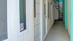 A corridor with doors, a staircase, and a QR code on a window. - OYO Life 92684 Kost Mutiara Nirwana (Karawang)