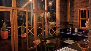 Una habitación acogedora con vigas de madera, un taburete verde, una mesa y una ventana con vistas a plantas.