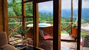 Una habitación de madera con ventanas amplias, un jacuzzi y una hamaca.
