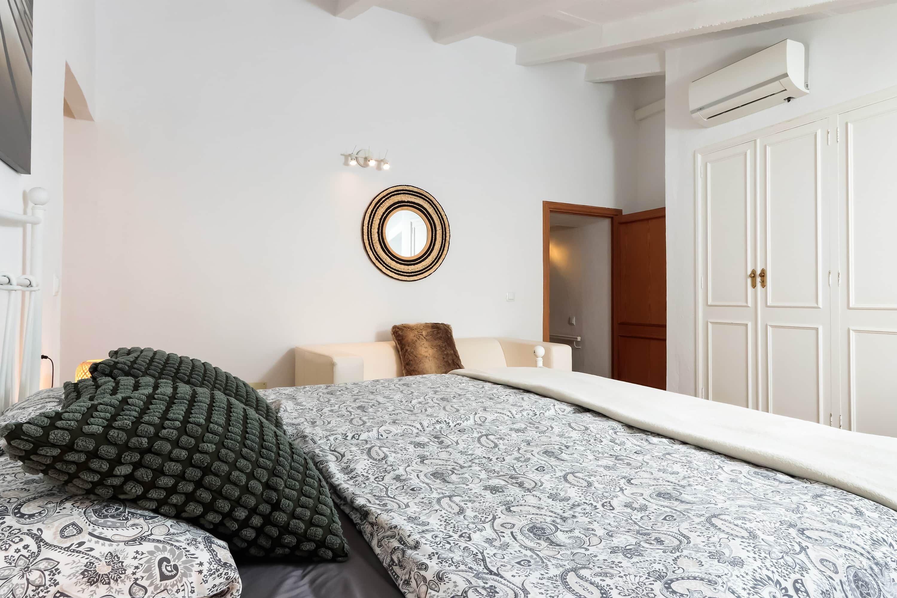 Un dormitorio con cama, espejo, armario y equipo de aire acondicionado.